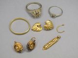 quelques bagues en or et d'autres bijoux posés sur une surface blanche