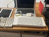 a desk with a laptop, tablet, and a keyboard on it