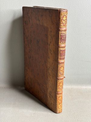 un vieux livre posé sur une table à côté d'un mur