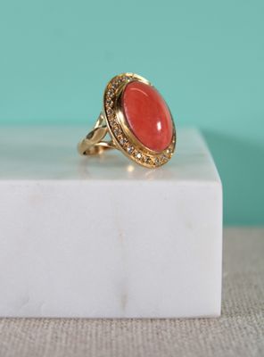 an image of a gold ring with a coral stone in the center