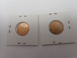 deux pièces d'or dans une boîte blanche posée sur une surface blanche