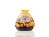 a yellow vase with flowers on it on a white surface