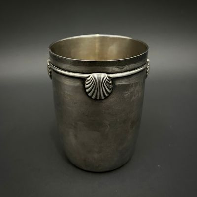 une coupe ancienne en argent avec une anse en forme de coquillage, sur fond noir
