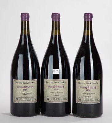 trois bouteilles de vin posées les unes à côté des autres sur une surface blanche