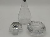 un petit vase en verre et un cendrier en verre posés sur une table blanche