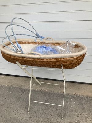 a wicker baby bassine on a stand in front of a garage