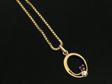 un collier en or orné d'une pierre rouge sur un fond noir
