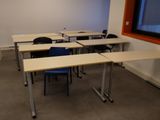 de nombreuses tables et chaises dans une pièce dotée d'une grande fenêtre