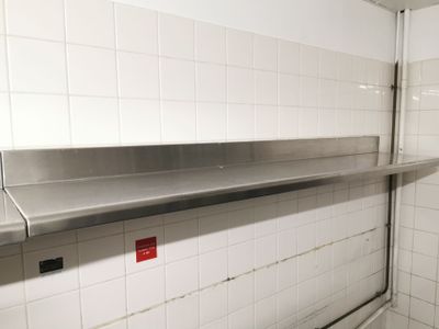 une étagère métallique au milieu d'une pièce carrelée de blanc