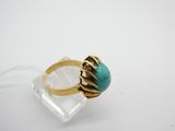 gros plan d'une bague en or avec une pierre turquoise
