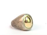 bague en argent et en or sur fond blanc, avec le reflet d'un immeuble