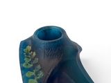 a blue vase with a plant on it on a white surface