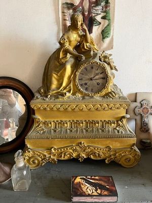 une horloge en or posée sur une table à côté d'un miroir