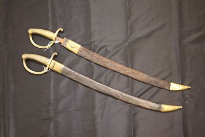 Il s'agit de deux paires de ciseaux posées sur un tissu noir, sur fond noir.