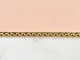 a close up of a gold chain on a marble surface