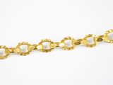gros plan d'un bracelet en or sur une surface blanche