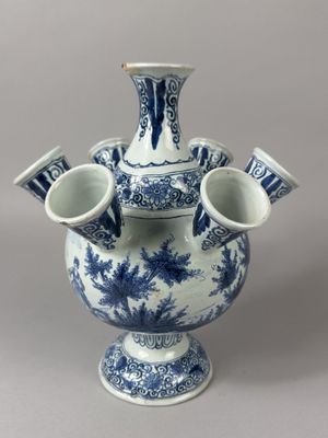 a blue and white vase with three cups in it