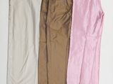 trois paires de pantalons sont alignées sur une surface blanche