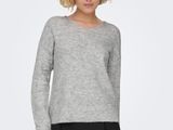 a woman in a grey sweater and black skirt stands in front of a white background