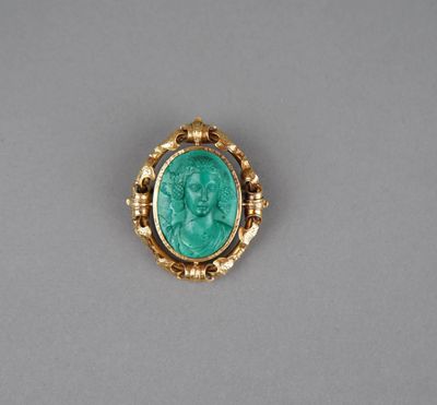 une broche en or ornée d'une pierre verte au centre