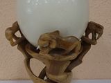 a white ball sitting on a wooden stand with a lamp on it