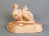 une statue représentant deux oiseaux perchés sur un bloc de bois