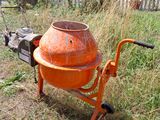 an orange cement mixer sitting in the grass