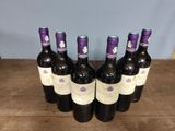 six bottles of wine are lined up on a wooden table