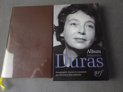 Le livre est posé sur une table, à côté d'une fleur jaune.