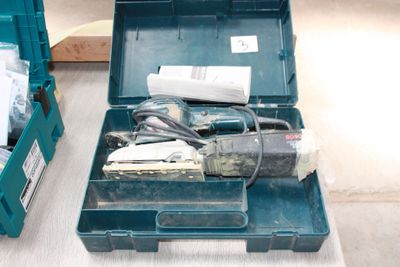a green tool box with tools in it on the floor