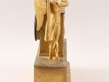 gold statue of an angel playing a trumpet on a wooden base