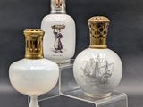 three white glass vases sitting on top of a clear stand