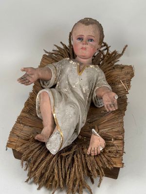 a small doll of a baby laying on a blanket