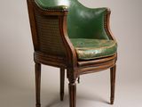 an old chair with a green leather seat and wooden legs