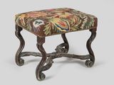 an ornate foot stool with a floral upholstered seat