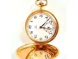 une montre de poche en or posée sur un miroir