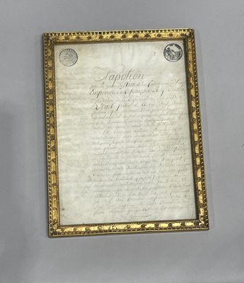 an old document with a gold frame on a white wall