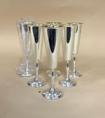 quatre verres à vin en argent sont alignés sur une table