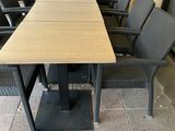 une longue table entourée de nombreuses chaises, sur le trottoir