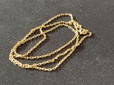 a close up of a gold chain necklace on a black surface