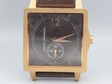 une montre en or avec un cadran noir et un bracelet en cuir marron