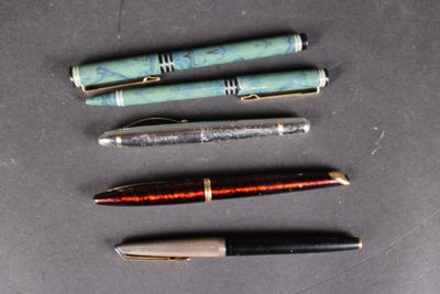 several pens are lined up on a table with a black background