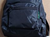 the back of a black backpack sitting on top of a brown floor