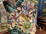 a vase with a painting on it sitting on a table
