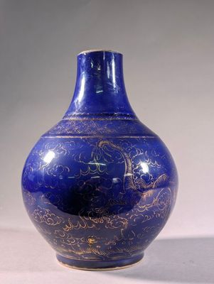 un vase bleu orné de motifs dorés posé sur une table