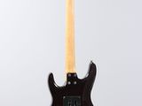 a black electric guitar hanging from a white wall