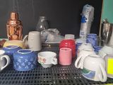 many cups and mugs sitting on a shelf