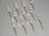six forks and two spoons are arranged in a row on a table
