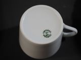 a white coffee cup with a green logo on it