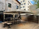 tables and umbrellas on the wooden deck outside of a building